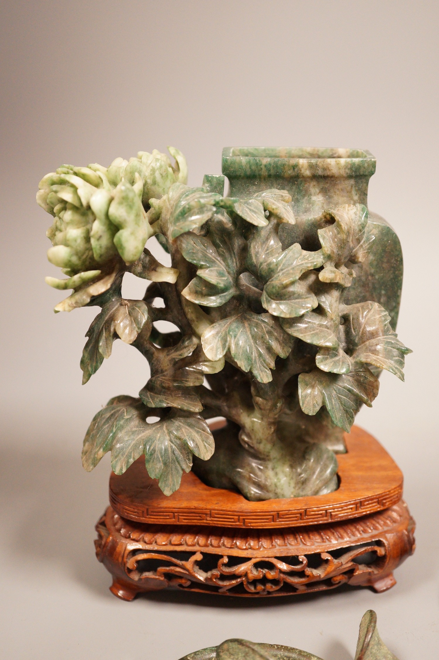 A Chinese bronze mirror, 11cm diameter, a jadeite floral carving on stand with a metal relief plaque, and a pair of bracelets